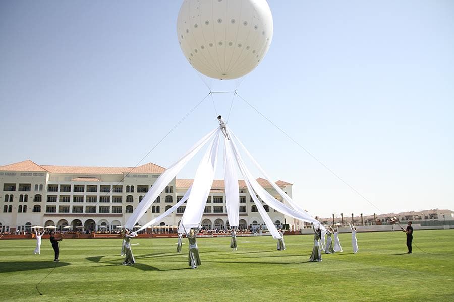 White helium balloon suspended above a polo field with white silk panels radiating down to ground dancers at the Julius Baer Polo Gold Cup